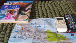 A travel guidebook, a remote control, and a map of Aruba on a textured green surface. - Studio Cadushi, Walking - 10 min from the beach (Noord)