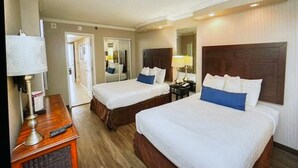Une chambre d’hôtel avec deux lits, un bureau avec une lampe et un miroir.