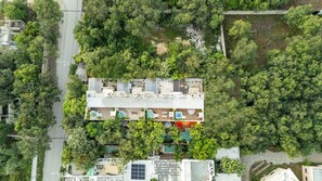 Vista aérea de un hotel de varios pisos, rodeado de abundante vegetación.