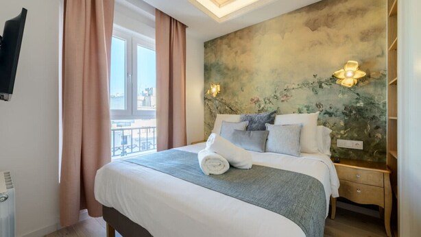 Ein Hotelzimmer mit einem großen Bett, Stadtblick und einem an der Wand befestigten Fernseher.