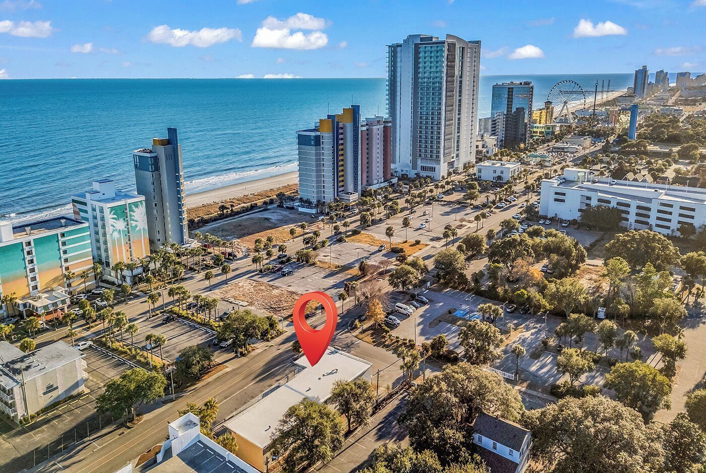 Vista aérea de una ciudad costera con rascacielos, una playa y una ubicación señalada.