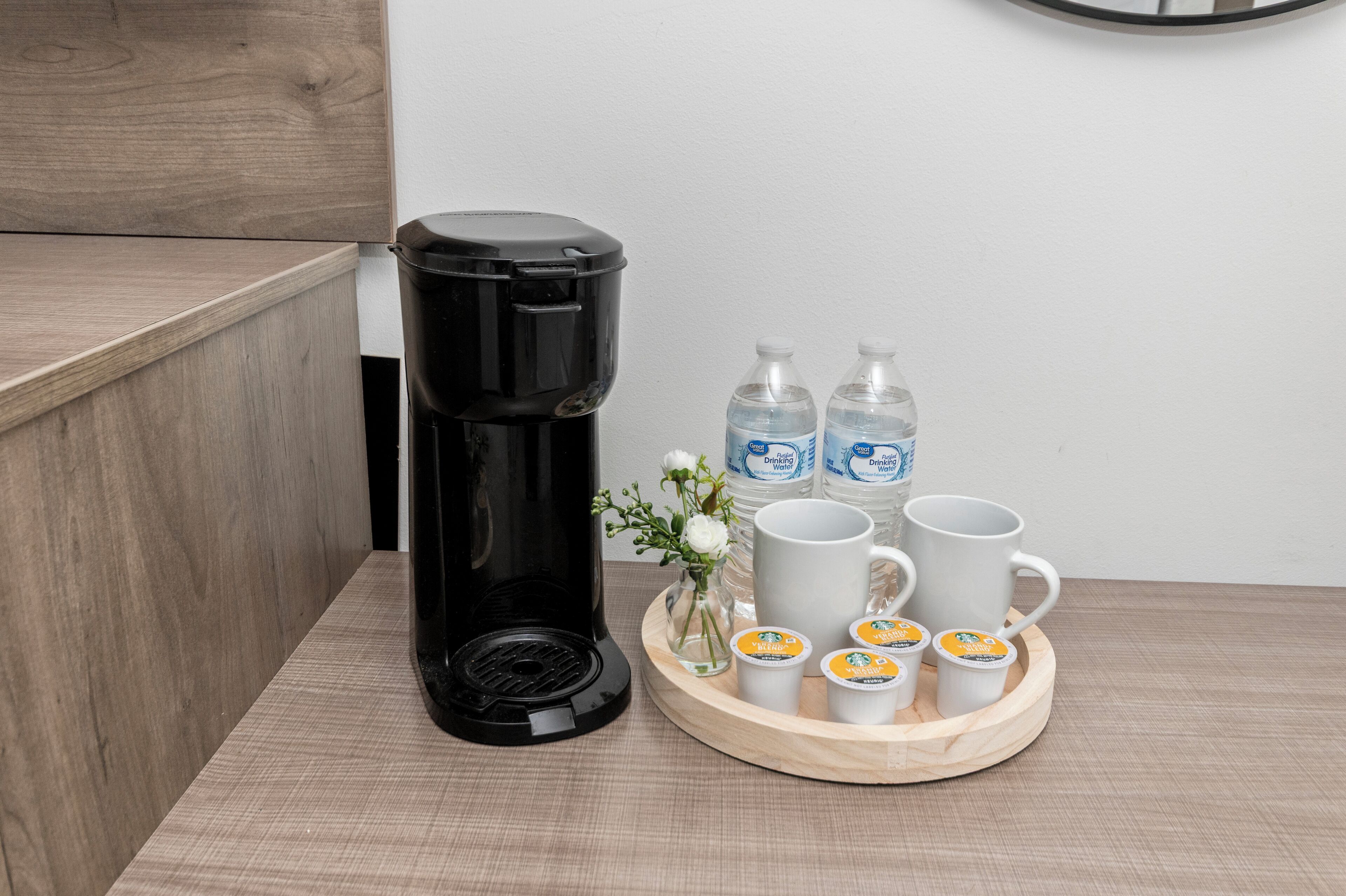Una cafetera, botellas de agua y tazas de café sobre una bandeja.