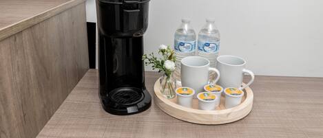 Una cafetera, botellas de agua y tazas de café sobre una bandeja.