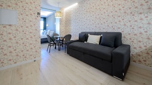 Ein modernes Wohnzimmer mit einem schwarzen Sofa, floralem Wandpapier und einem Oberlicht.