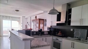 A modern kitchen with white cabinets, a central island, a microwave, a coffee maker, and a stove.