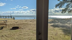 Uitzicht op het strand vanaf een kamer, met een houten bankje en een metalen prullenbak.