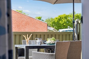 An outdoor patio with wicker furniture, a table set with a pitcher, glasses, and a bowl of mushrooms.