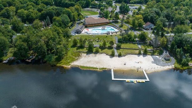 An aerial view of a lakeside property with a swimming pool, a beach, and a dock. - Lake View/Pool/Beach/Fire Pit/Game Room (Tobyhanna)