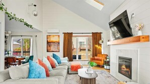 A modern living room with a fireplace, a sofa set, and a dining area visible through a glass door. - Lake View/Pool/Beach/Fire Pit/Game Room (Tobyhanna)