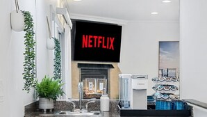 A modern kitchen with white cabinets, a granite countertop, a coffee machine, and a sign that reads "NETFLIX". - Designer Beach Home, Rooftop Deck, Free Parking, Bike Rentals, King Suites (Newport Beach)