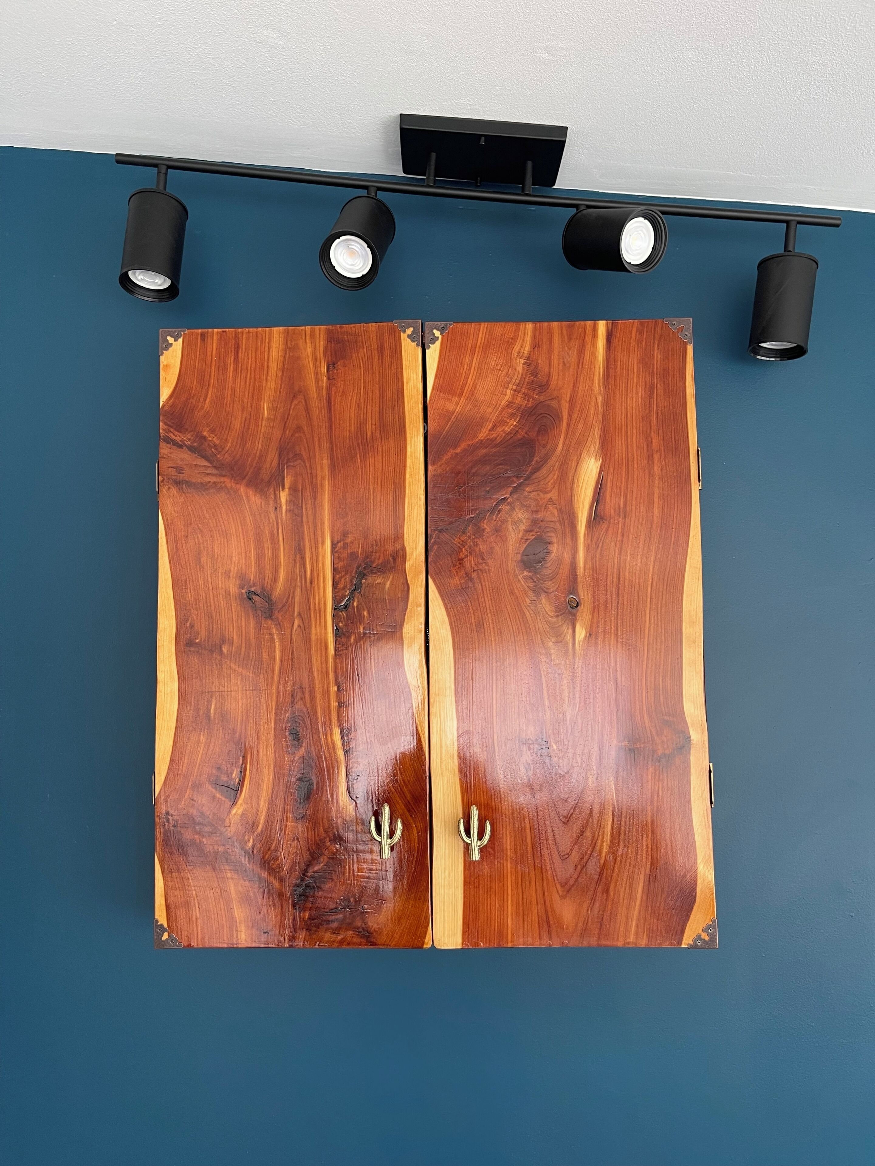 Un armario de madera con dos puertas y un estante negro encima.