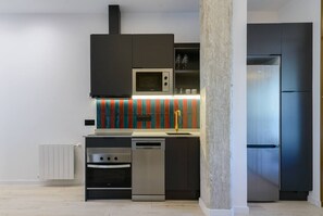 Eine moderne Küche mit integriertem Mikrowellenherd, Backofen und Geschirrspüler, einem Kühlschrank und einer farbenfrohen Spritzschutzwand.
