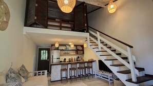 Une cuisine moderne avec un coin bar, un escalier en bois et des luminaires suspendus.