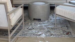 Un'area salotto esterna accogliente con un divano imbottito, due poltrone in vimini e un tavolino rotondo.