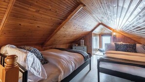 Ein gemütliches Schlafzimmer im Dachgeschoss mit zwei Betten, Holzbalken und einem Oberlicht.