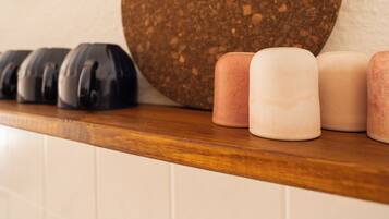 A countertop with a round corkboard, a row of black and pink candles, and a wooden shelf.