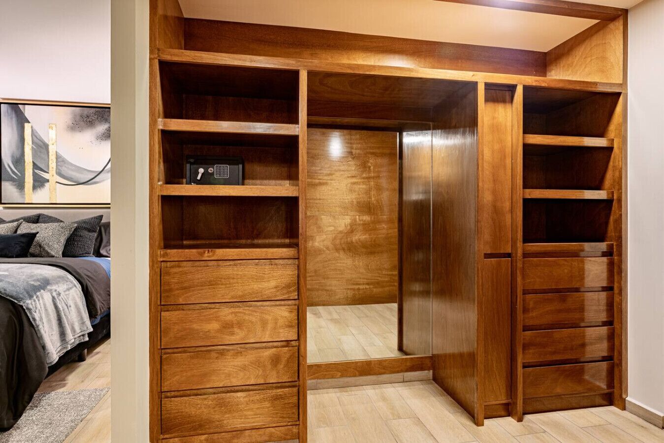 Un dressing avec de nombreuses étagères et tiroirs, un miroir et un petit coffre-fort.