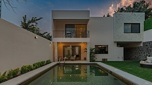 Une maison moderne à deux étages, dotée d’une piscine, d’un espace extérieur aménagé et d’une pelouse bien entretenue.