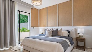 Une chambre moderne avec un grand lit, une table de chevet avec une lampe et une vue sur la verdure.