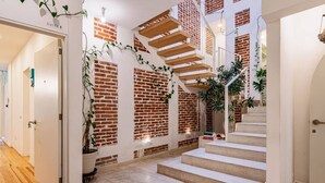 A modern interior with a brick wall, wooden staircase, and potted plants.
