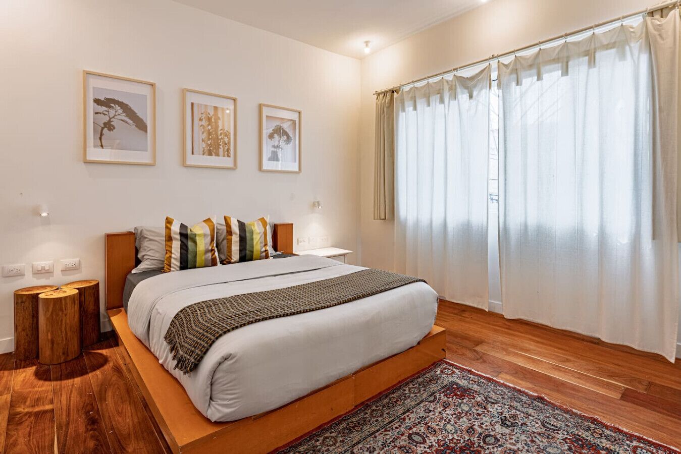 Um quarto moderno com uma cama grande, cabeceira de madeira e tapete estampado.