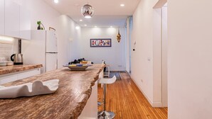 A modern kitchen with white cabinets, a marble countertop, and a wooden floor.