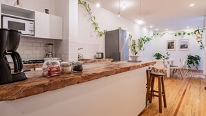 A modern kitchen with white cabinets, a wooden countertop, and a dining area with a white table and chairs.