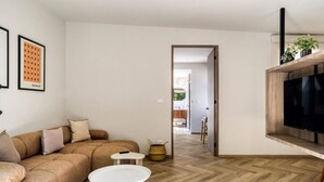 Un salon moderne avec un canapé, une table basse et un téléviseur fixé sur une étagère en bois.