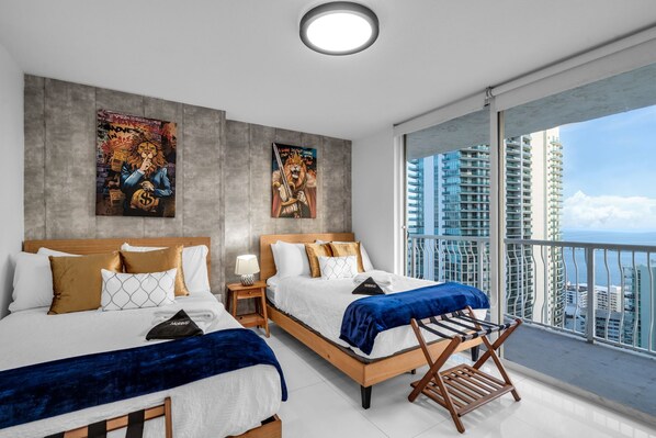 A modern hotel room with two beds, a balcony with a city view, and artwork on the walls. - High Rise Ocean View Condo, Pool, Hot Tub, Game Room, Close to Food and Mall (Miami)