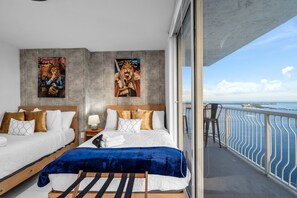 A modern hotel room with two beds, a balcony with a railing, and a view of the sea. - High Rise Ocean View Condo, Pool, Hot Tub, Game Room, Close to Food and Mall (Miami)