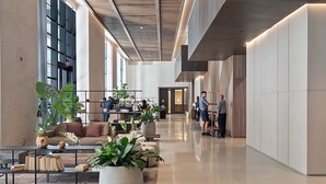 Eine geräumige Lobby mit modernem Design, ausgestattet mit einer langen Rezeption, gemütlichen Sitzbereichen und großen Topfpflanzen.