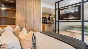 A modern bedroom with a large bed, wooden wardrobe, and a kitchen area visible through an open door. - Escape to Skyline Views & Rooftop Pool Bliss (Mexico City)