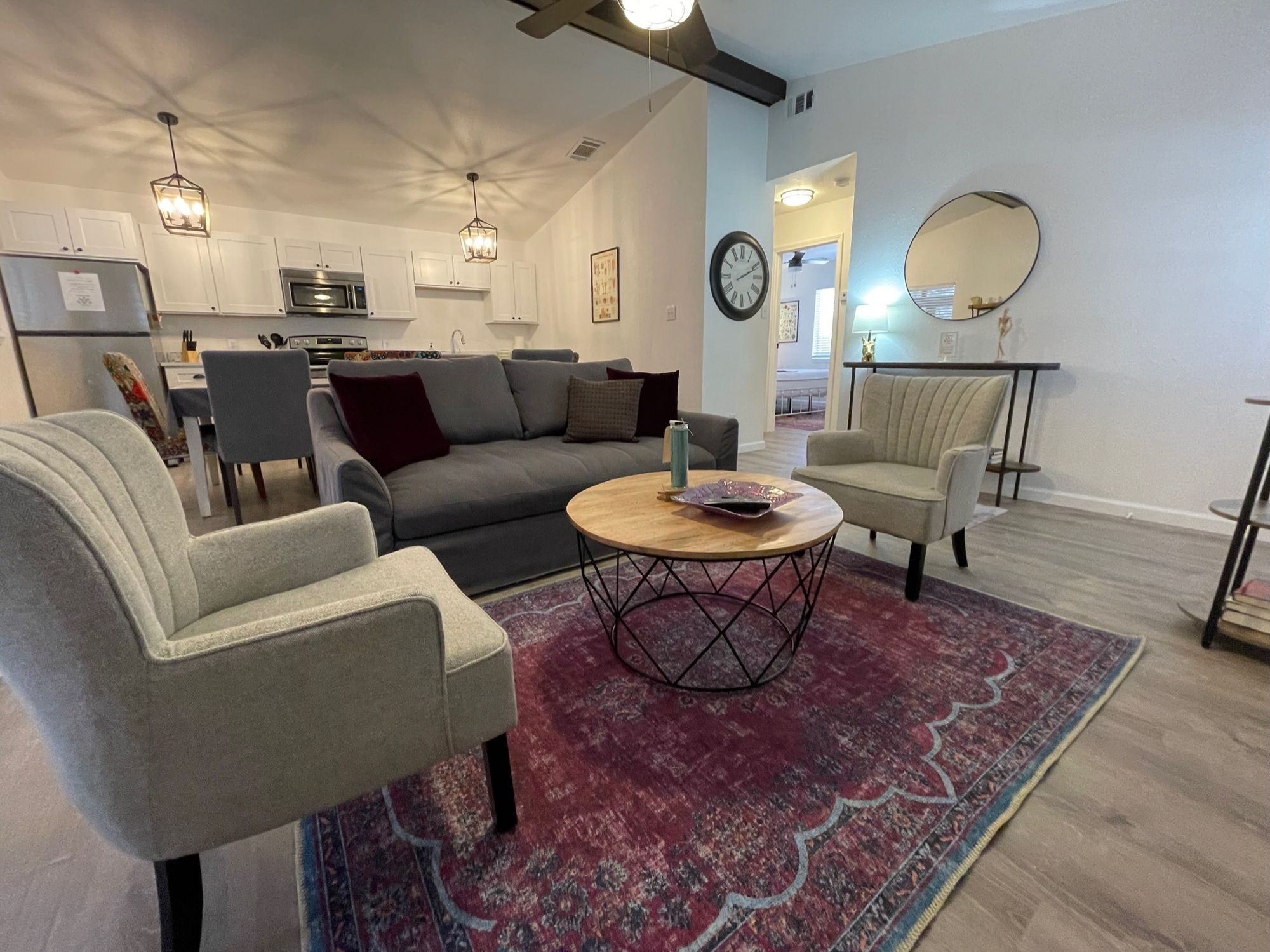 A modern living room with a sofa, two armchairs, a coffee table, and a rug.