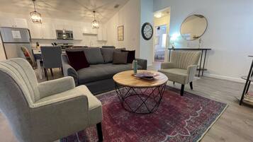 A modern living room with a sofa, two armchairs, a coffee table, and a rug.