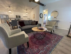 A modern living room with a sofa, two armchairs, a coffee table, and a rug. - Cottage 9 Amethyst, Pet-Friendly Two-Bedroom Creek-Facing Cottage (Wimberley)