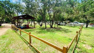 A fenced park area with a wooden pavilion and picnic tables.