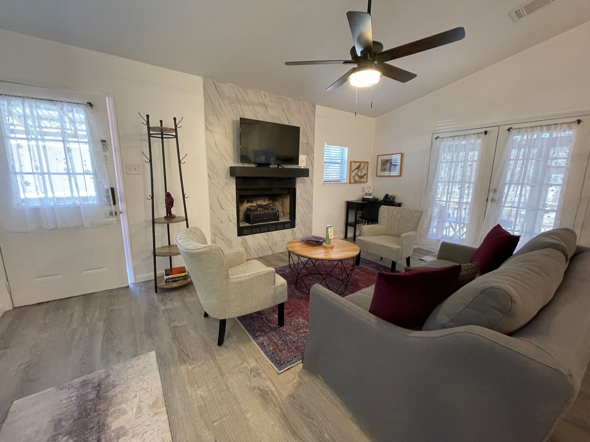 A living room with a fireplace, a ceiling fan, and a television.