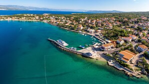 Vue aérienne d’une ville côtière avec un port de plaisance, des maisons et des eaux d’un bleu limpide.