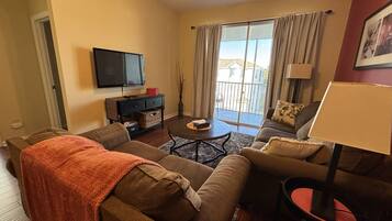 A living room with a sofa, a coffee table, and a TV mounted on the wall.