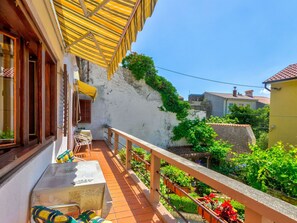 A balcony with a tiled floor, a table with chairs, and a yellow striped awning. - CIRO CH / HR-07098-04 by Interhome (Selce)