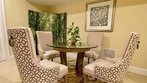 A dining area with a round glass table surrounded by four patterned chairs.