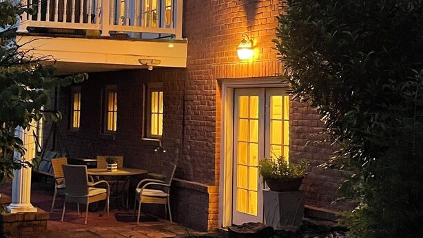 A two-story house with a balcony, a patio with outdoor seating, and a brick exterior.