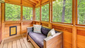 A wooden cabin with a built-in sofa, large windows, and a view of a forest. - Hike & Bike! Peaceful Wooded Retreat in Old Fort (Old Fort)