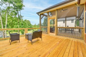 A wooden deck with outdoor furniture, a glass enclosure, and a view of a house. - Hike & Bike! Peaceful Wooded Retreat in Old Fort (Old Fort)