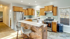 A modern kitchen with wooden cabinets, stainless steel appliances, and a bar area. - Hike & Bike! Peaceful Wooded Retreat in Old Fort (Old Fort)