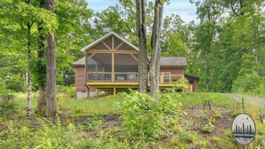 A two-story cabin with a large balcony, surrounded by trees. - Hike & Bike! Peaceful Wooded Retreat in Old Fort (Old Fort)
