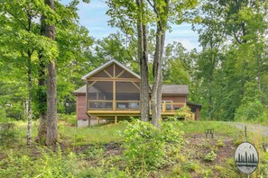 A two-story cabin with a large balcony, surrounded by trees. - Hike & Bike! Peaceful Wooded Retreat in Old Fort (Old Fort)