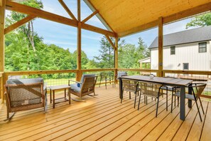 A wooden deck with outdoor furniture, a covered area, and a view of a house and trees. - Hike & Bike! Peaceful Wooded Retreat in Old Fort (Old Fort)