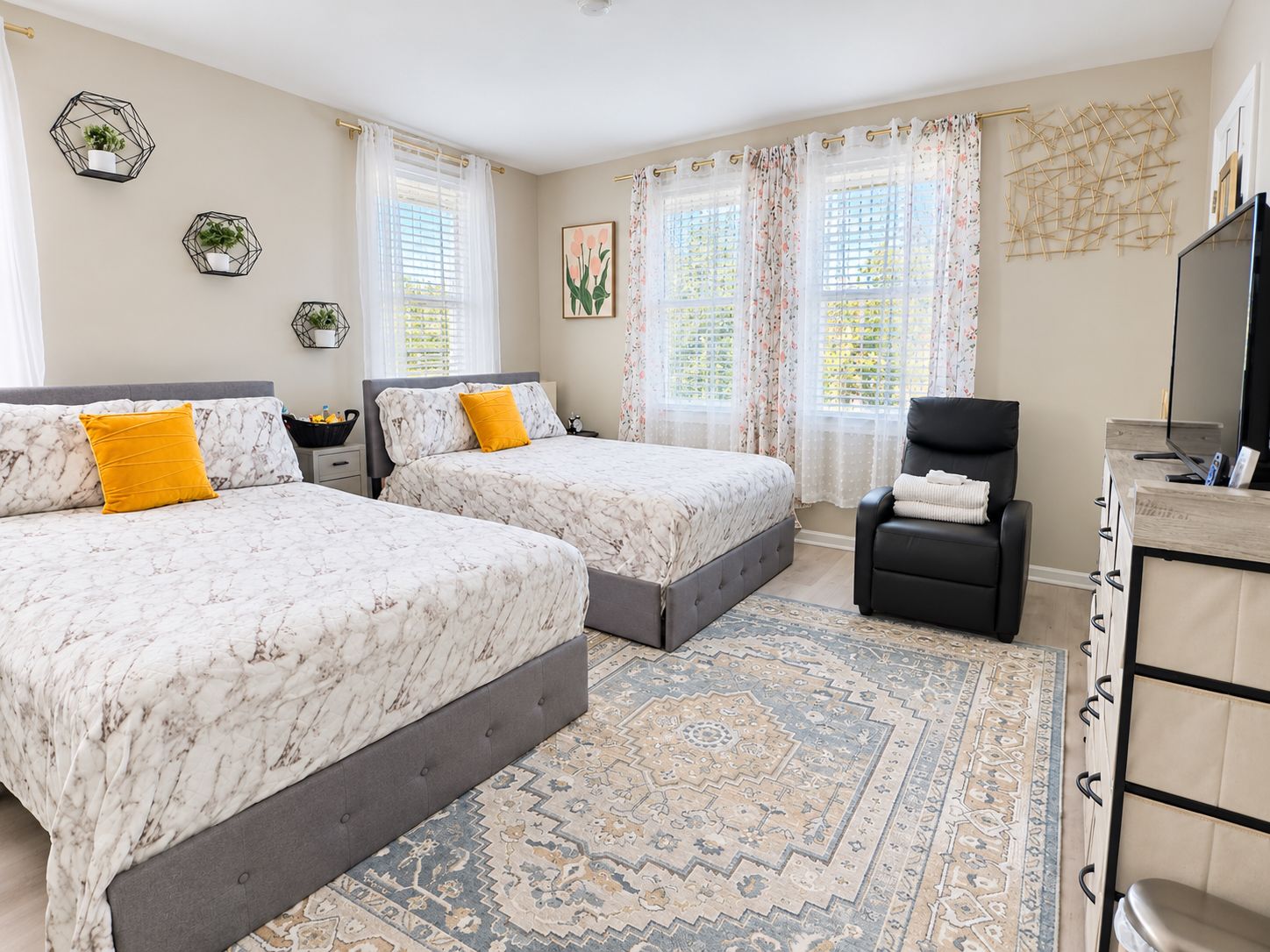 A double room with two beds, a desk, a chair, and a TV.