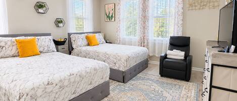 A double room with two beds, a desk, a chair, and a TV.